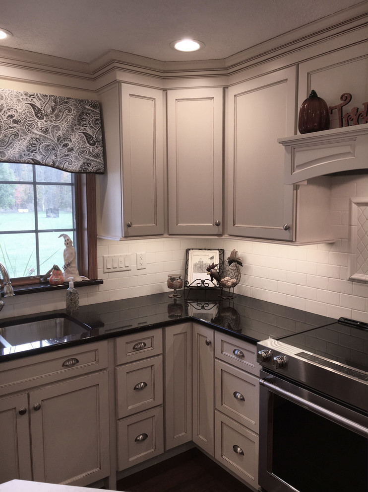 Eat-in kitchen - large transitional medium tone wood floor and brown floor eat-in kitchen idea with an undermount sink, flat-panel cabinets, white cabinets, granite countertops, white backsplash, porcelain backsplash, stainless steel appliances and an island