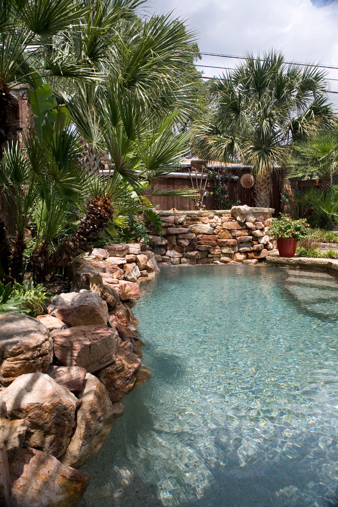 Photo of a small country backyard custom-shaped natural pool in Austin with natural stone pavers and a hot tub.