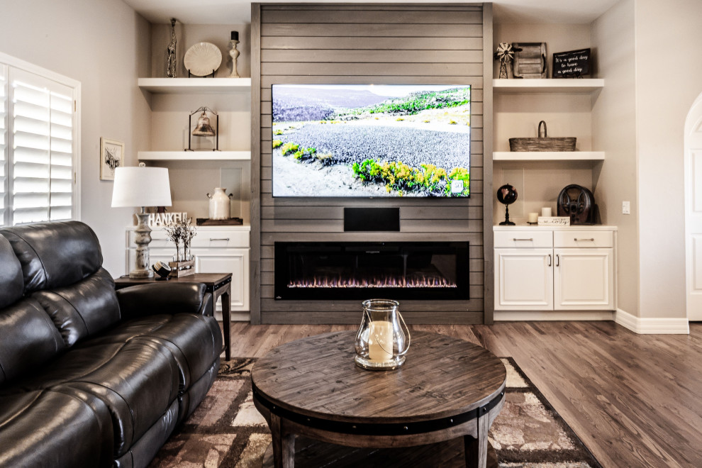 Exempel på ett mellanstort lantligt allrum med öppen planlösning, med grå väggar, mellanmörkt trägolv, en bred öppen spis, en väggmonterad TV och brunt golv