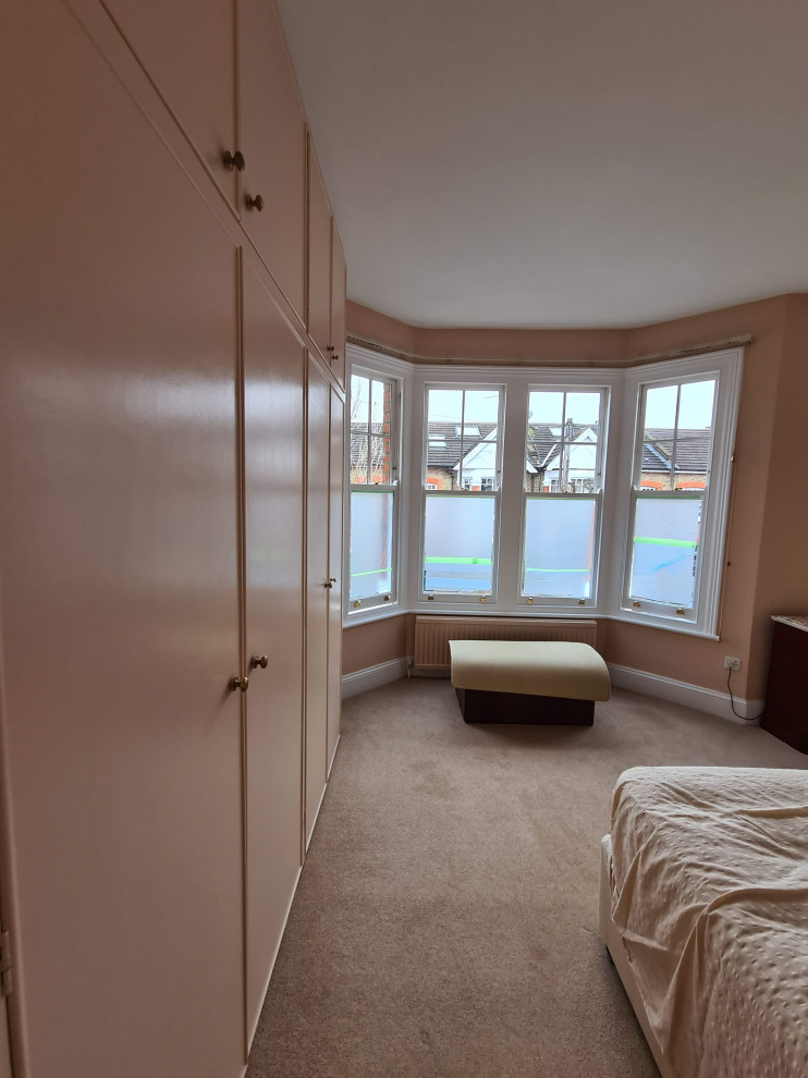 Imagen de dormitorio principal clásico grande con paredes rosas, moqueta, suelo beige y bandeja