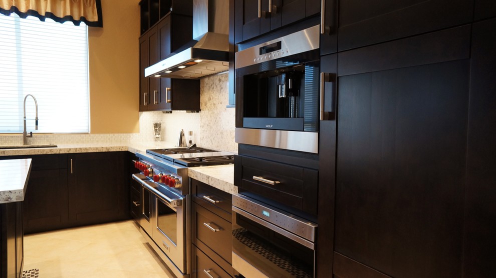 Inspiration for a transitional l-shaped porcelain tile and beige floor kitchen remodel in Phoenix with an undermount sink, recessed-panel cabinets, dark wood cabinets, quartz countertops, white backsplash, ceramic backsplash, stainless steel appliances and an island