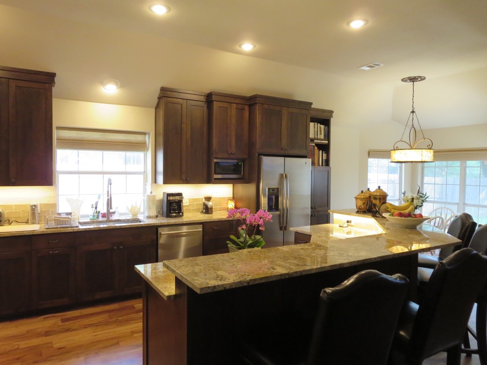 Large transitional medium tone wood floor and brown floor eat-in kitchen photo in Austin with an undermount sink, shaker cabinets, dark wood cabinets, granite countertops, multicolored backsplash, ceramic backsplash, stainless steel appliances and an island