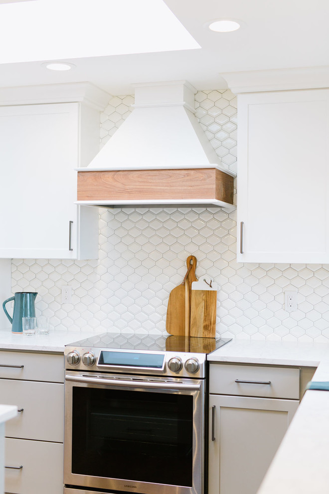 Inspiration for a mid-sized transitional u-shaped medium tone wood floor and brown floor open concept kitchen remodel with an undermount sink, shaker cabinets, white cabinets, quartz countertops, white backsplash, porcelain backsplash, stainless steel appliances, an island and white countertops