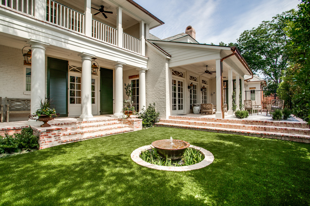 Photo of a large mediterranean backyard partial sun garden in Dallas with brick pavers and a water feature.