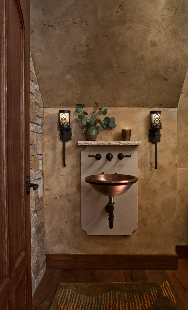 Photo of a mid-sized traditional powder room in Detroit with dark hardwood floors, brown floor, brown tile, stone tile, beige walls, a wall-mount sink and beige benchtops.
