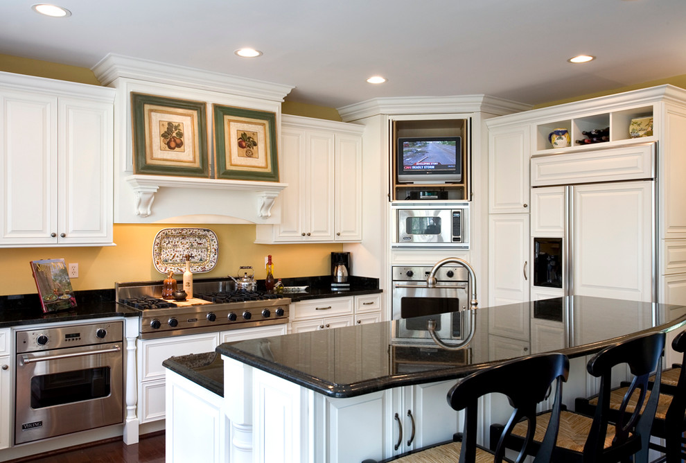 Traditional u-shaped eat-in kitchen in Chicago with raised-panel cabinets, white cabinets and stainless steel appliances.