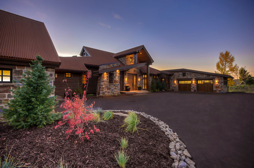 Expansive country two-storey brown house exterior in Salt Lake City with stone veneer, a gable roof and a metal roof.