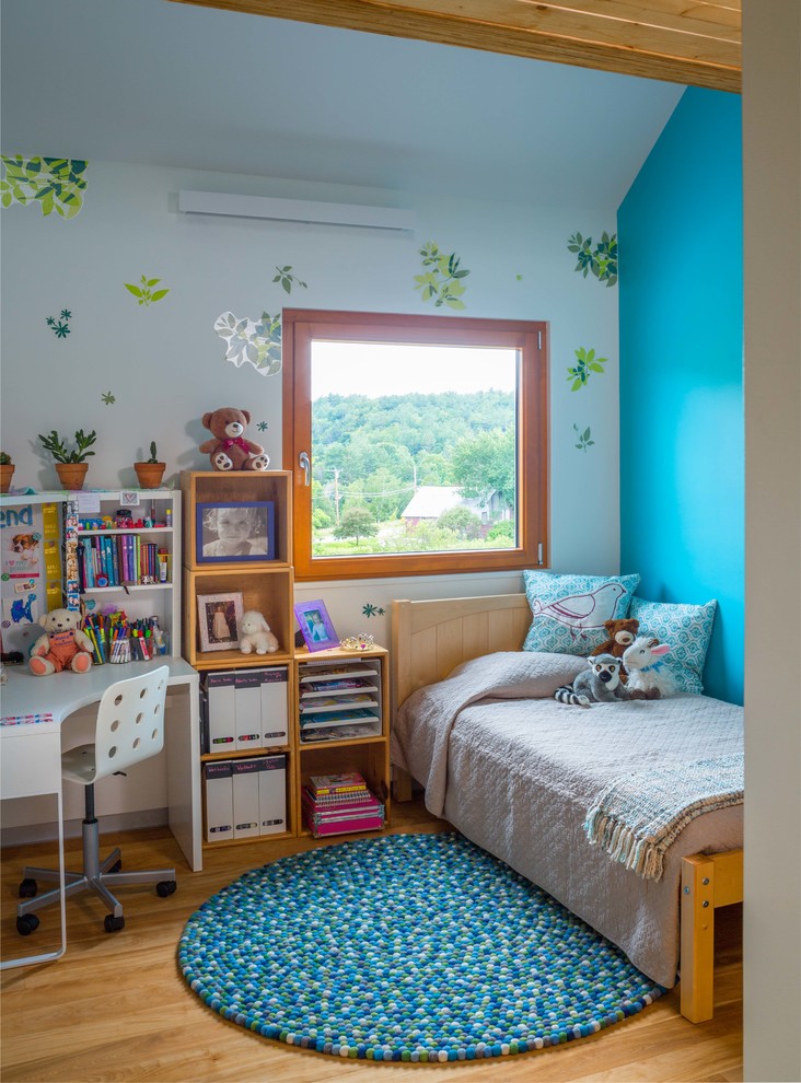 This is an example of a small modern kids' bedroom for kids 4-10 years old and girls in Other with blue walls, medium hardwood floors and brown floor.