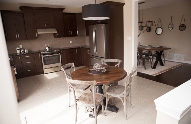 Example of a mountain style ceramic tile open concept kitchen design with a farmhouse sink, shaker cabinets, dark wood cabinets, granite countertops, brown backsplash, marble backsplash, stainless steel appliances and no island