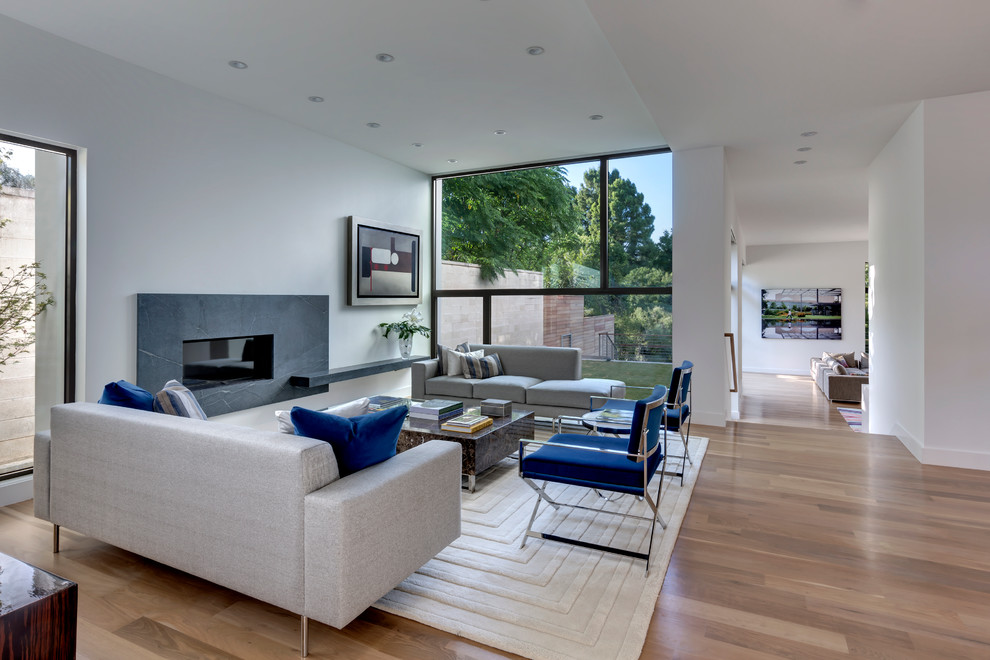 This is an example of a mid-sized modern open concept living room in Dallas with white walls, light hardwood floors, a ribbon fireplace and a stone fireplace surround.