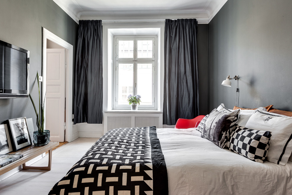 This is an example of a large scandinavian master bedroom in Stockholm with black walls, painted wood floors and no fireplace.