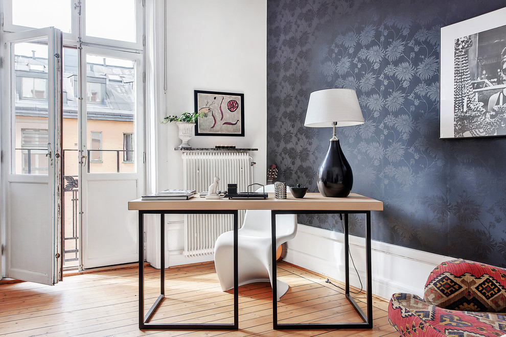 Photo of a mid-sized scandinavian study room in Stockholm with black walls, medium hardwood floors, a freestanding desk and no fireplace.