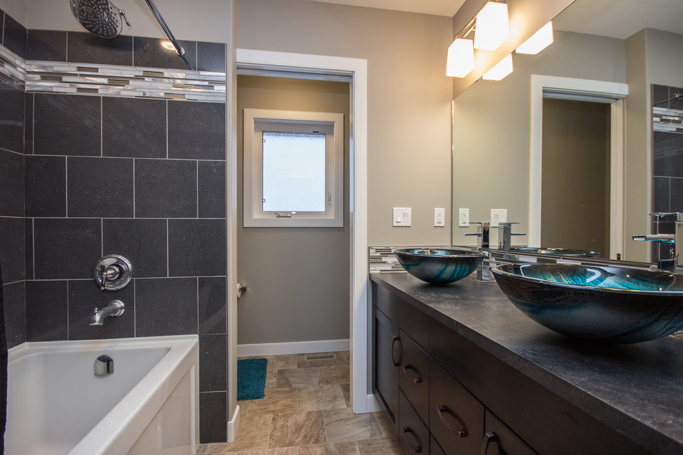 Design ideas for a mid-sized contemporary master bathroom in Calgary with shaker cabinets, dark wood cabinets, an alcove tub, a shower/bathtub combo, gray tile, glass tile, grey walls, limestone floors, a vessel sink and zinc benchtops.