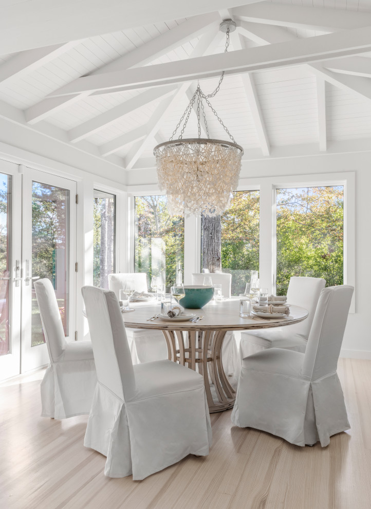 This is an example of a beach style dining room in Boston with white walls, light hardwood floors and beige floor.