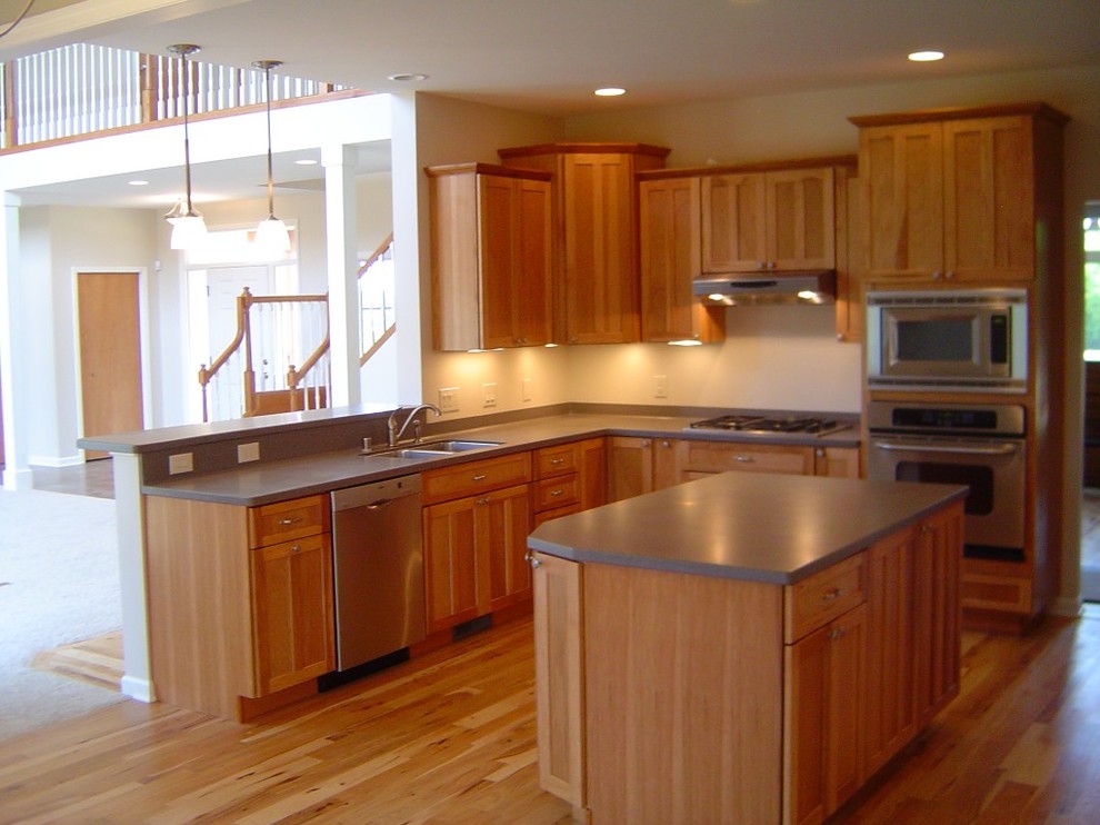 Eat-in kitchen - mid-sized transitional u-shaped medium tone wood floor eat-in kitchen idea with a double-bowl sink, shaker cabinets, medium tone wood cabinets, solid surface countertops, stainless steel appliances and an island