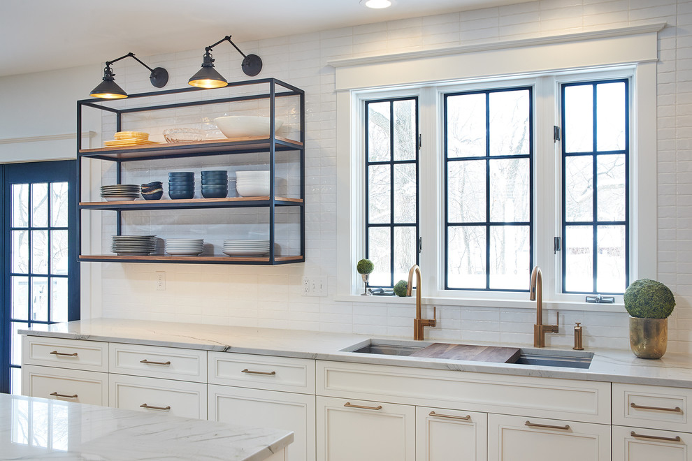 Large transitional l-shaped eat-in kitchen in Minneapolis with an undermount sink, flat-panel cabinets, white cabinets, quartzite benchtops, white splashback, subway tile splashback, stainless steel appliances, light hardwood floors, with island, yellow floor and white benchtop.