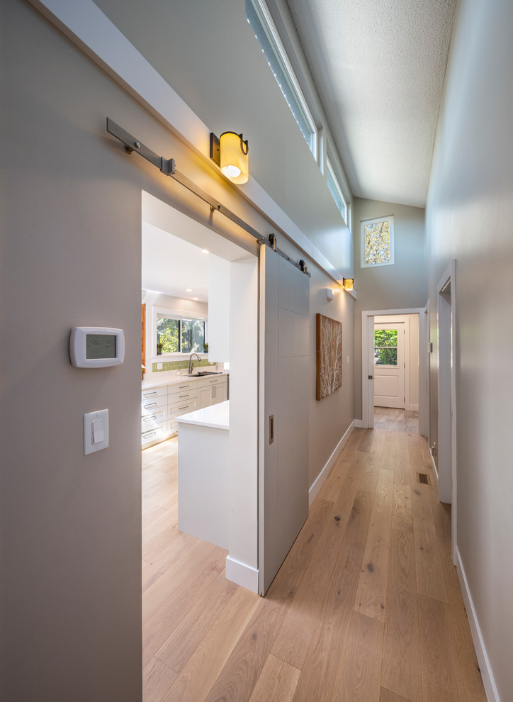 This is an example of a mid-sized transitional hallway in Vancouver with white walls, light hardwood floors and beige floor.