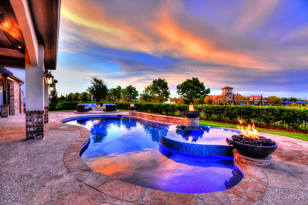 Large country backyard custom-shaped lap pool in Houston with a hot tub and natural stone pavers.