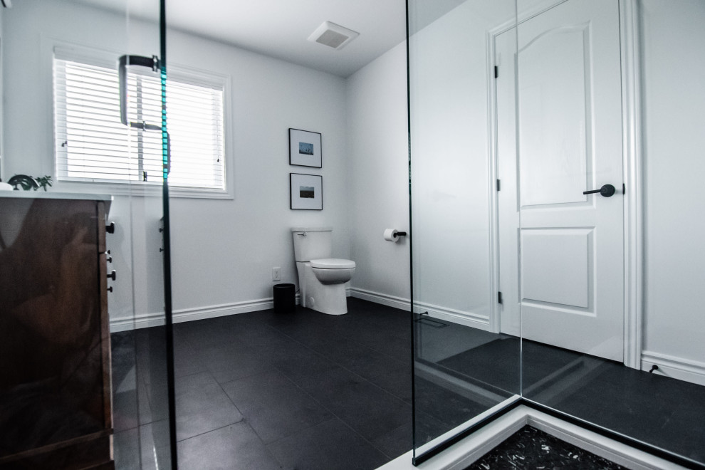 This is an example of a mid-sized contemporary master bathroom in Ottawa with shaker cabinets, dark wood cabinets, a corner shower, a two-piece toilet, white tile, ceramic tile, white walls, porcelain floors, an undermount sink, engineered quartz benchtops, black floor, a hinged shower door and white benchtops.