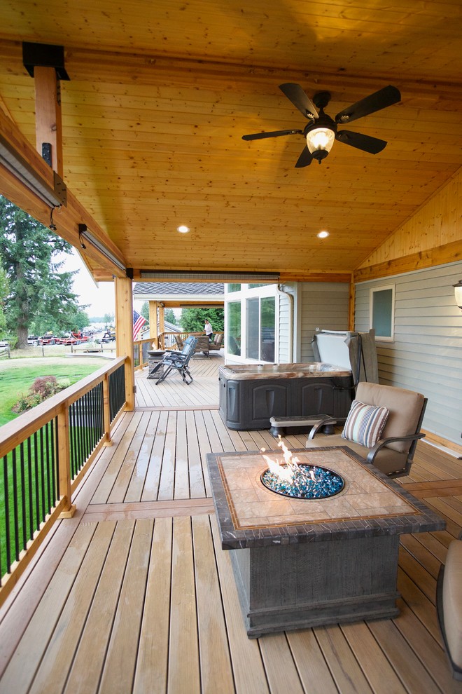 This is an example of a large country backyard deck in Seattle with a roof extension and a fire feature.