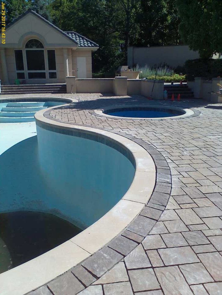 Example of a large classic backyard concrete paver and kidney-shaped hot tub design in Omaha