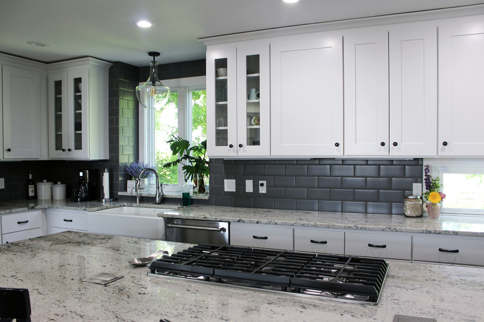 Inspiration for a large transitional l-shaped brown floor eat-in kitchen remodel with a farmhouse sink, shaker cabinets, white cabinets, quartz countertops, gray backsplash, subway tile backsplash, stainless steel appliances, an island and multicolored countertops