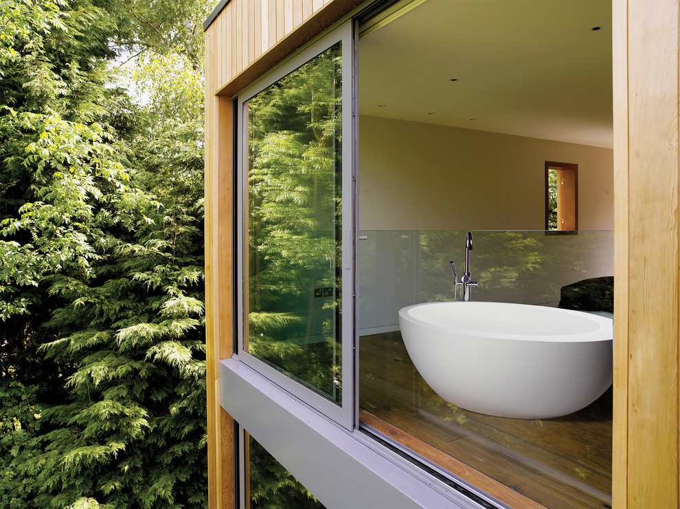 Example of a mid-sized mountain style master medium tone wood floor freestanding bathtub design with beige walls