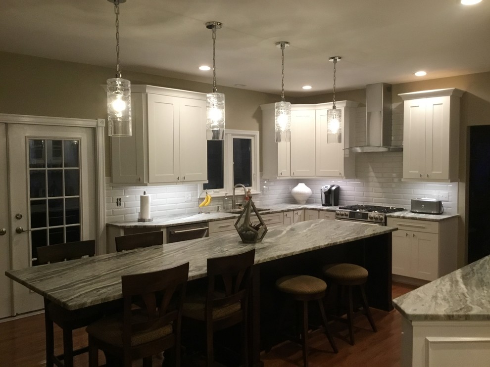 Example of a mid-sized transitional u-shaped medium tone wood floor and brown floor open concept kitchen design in DC Metro with an undermount sink, shaker cabinets, white cabinets, granite countertops, white backsplash, subway tile backsplash, stainless steel appliances, an island and gray countertops