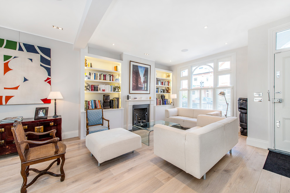 This is an example of a mid-sized scandinavian formal open concept living room in London with white walls, light hardwood floors and a standard fireplace.
