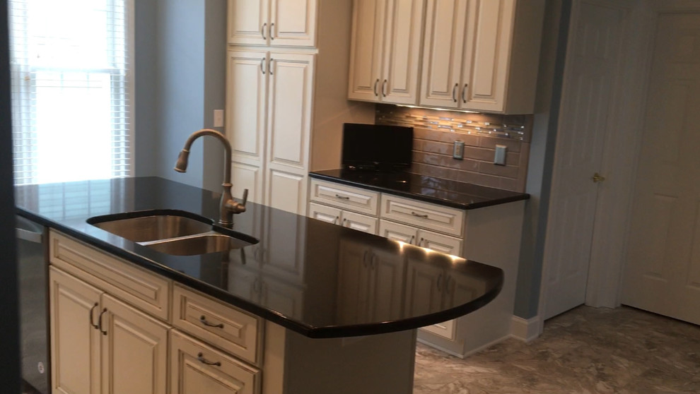 Mid-sized vinyl floor kitchen photo with an undermount sink, raised-panel cabinets, distressed cabinets, ceramic backsplash, stainless steel appliances and an island