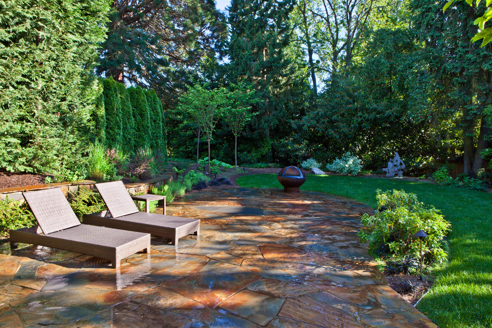 This is an example of a contemporary patio in Seattle with a fire feature and natural stone pavers.