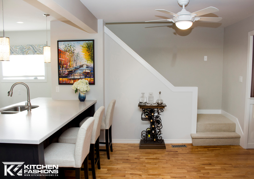 Example of a mid-sized transitional single-wall ceramic tile open concept kitchen design with an undermount sink, shaker cabinets, gray cabinets, solid surface countertops, gray backsplash, mosaic tile backsplash, white appliances and an island