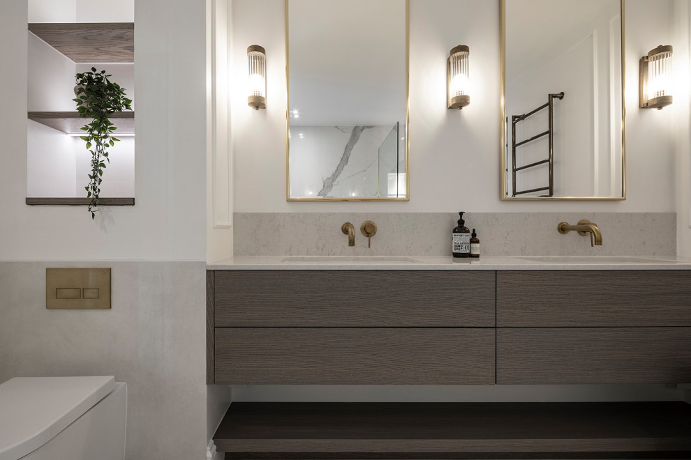 This is an example of a mid-sized transitional master bathroom in London with flat-panel cabinets, dark wood cabinets, a freestanding tub, an open shower, a wall-mount toilet, white tile, porcelain tile, white walls, porcelain floors, an integrated sink, engineered quartz benchtops, white floor, an open shower, beige benchtops, a double vanity and a floating vanity.
