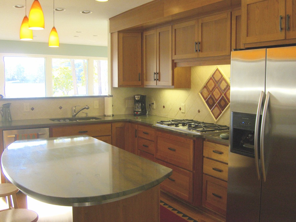 Example of a mid-sized transitional l-shaped eat-in kitchen design in Raleigh with an undermount sink, shaker cabinets, medium tone wood cabinets, granite countertops, beige backsplash, stone tile backsplash, stainless steel appliances and an island