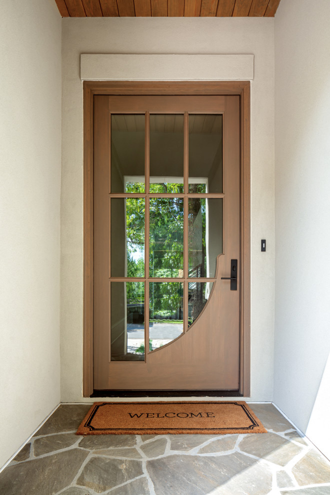 На фото: прихожая с полом из известняка, одностворчатой входной дверью, коричневой входной дверью, разноцветным полом и деревянным потолком