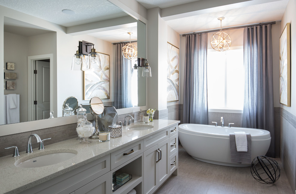 This is an example of a mid-sized transitional master bathroom in Calgary with shaker cabinets, white cabinets, a freestanding tub, beige tile, beige walls, porcelain floors, an undermount sink and beige floor.