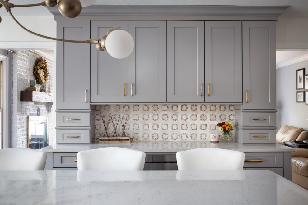 Example of a transitional dark wood floor and brown floor kitchen design with a drop-in sink, shaker cabinets, gray cabinets, quartzite countertops, white backsplash, mosaic tile backsplash, stainless steel appliances, an island and white countertops