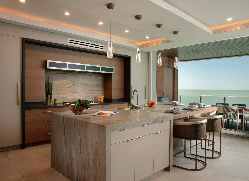 Example of a trendy galley gray floor and tray ceiling kitchen design with an undermount sink, flat-panel cabinets, medium tone wood cabinets, gray backsplash, stone slab backsplash, an island and gray countertops