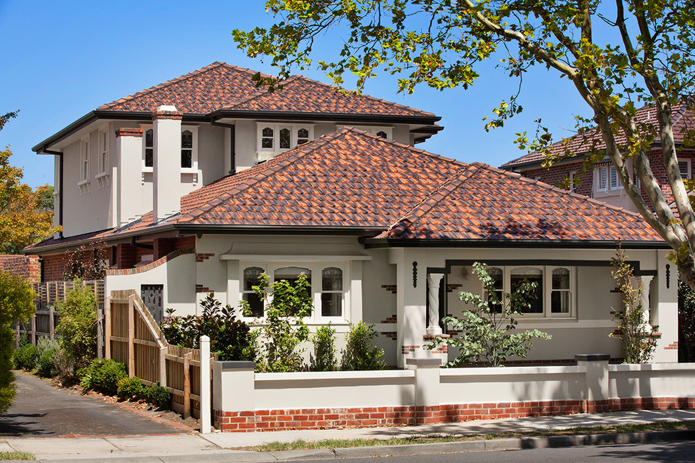 Photo of a large mediterranean two-storey beige exterior in Melbourne with a hip roof.