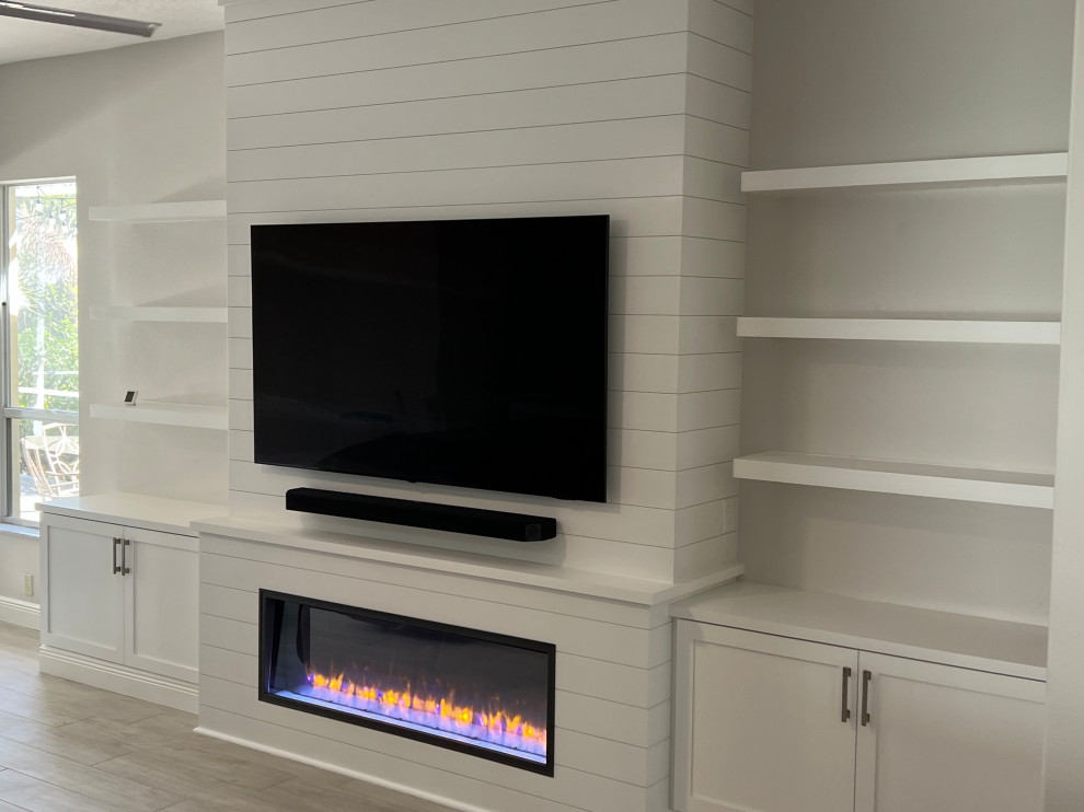 Photo of a large games room in Tampa with grey walls, ceramic flooring, a standard fireplace, a timber clad chimney breast, a wall mounted tv, grey floors, tongue and groove walls and feature lighting.