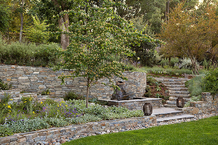 This is an example of a mid-sized country backyard partial sun formal garden for summer in San Francisco with a water feature and natural stone pavers.