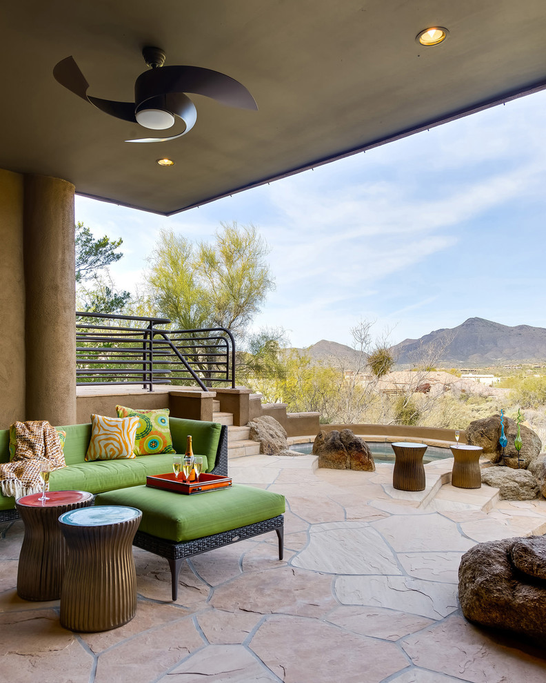 Backyard patio in Phoenix with a water feature, natural stone pavers and a roof extension.