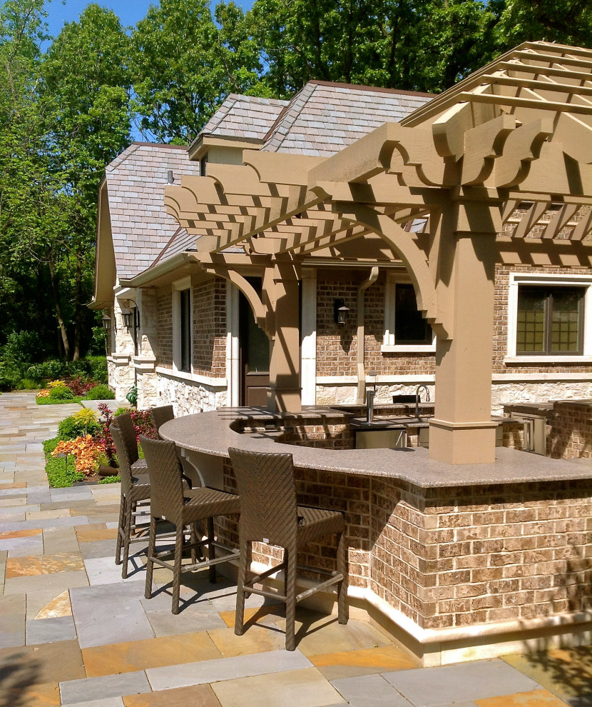 Large transitional patio in Chicago with an outdoor kitchen, natural stone pavers and a pergola.