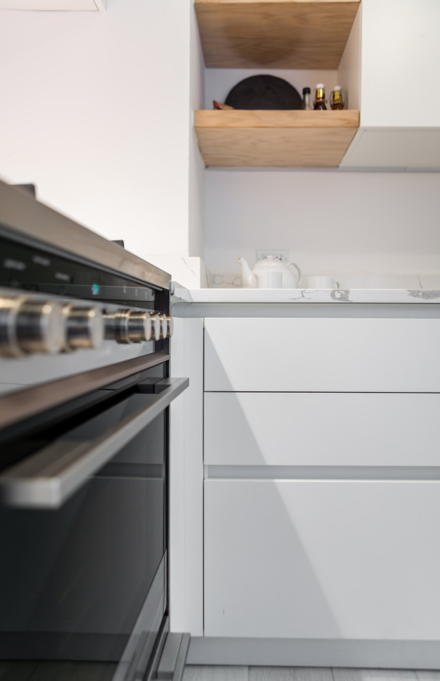Example of a mid-sized transitional l-shaped light wood floor enclosed kitchen design in Chicago with an undermount sink, flat-panel cabinets, white cabinets, marble countertops, white backsplash, subway tile backsplash, stainless steel appliances, no island and white countertops