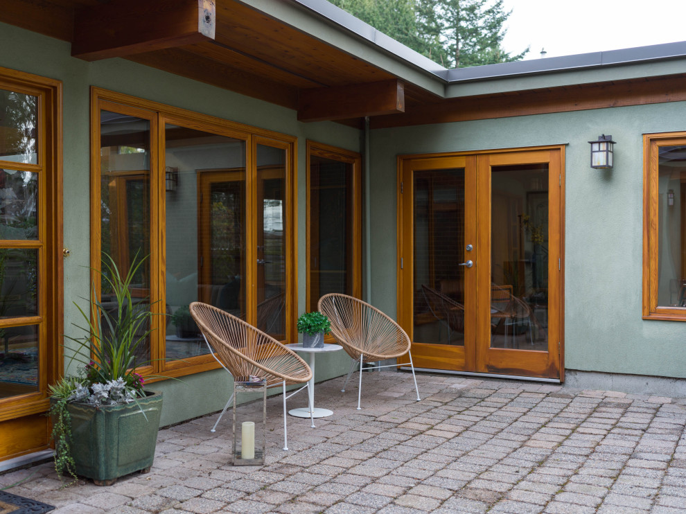 Design ideas for a midcentury green house exterior in Vancouver with a flat roof.