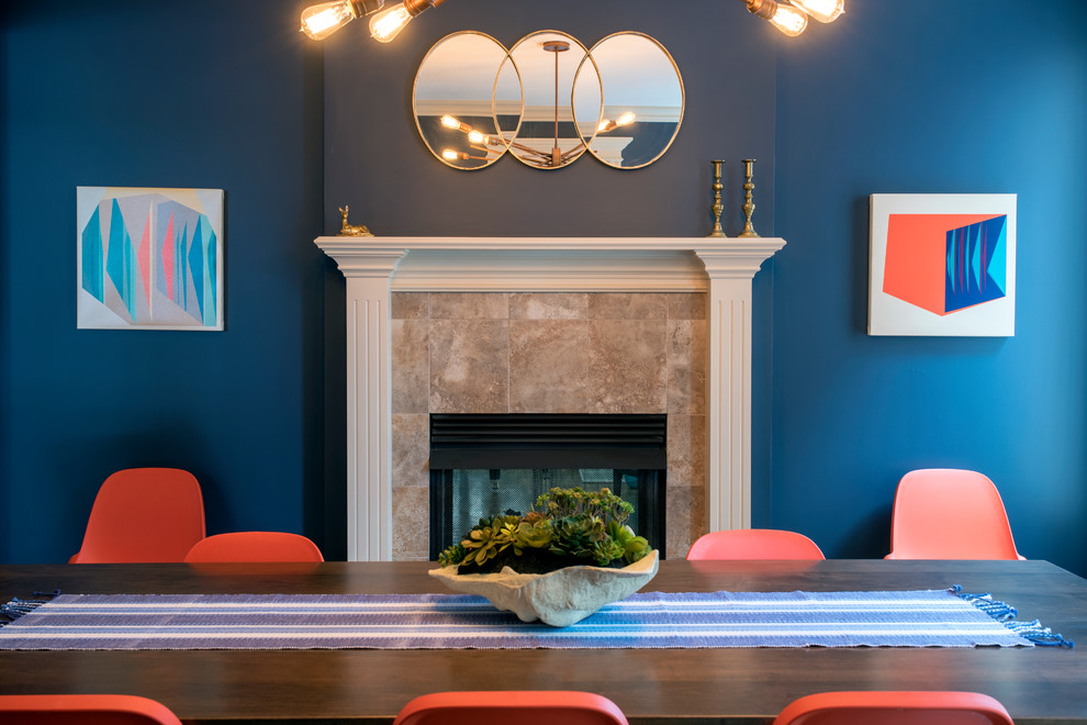 Photo of a mid-sized modern separate dining room in Kansas City with blue walls, dark hardwood floors, a standard fireplace, a tile fireplace surround and brown floor.