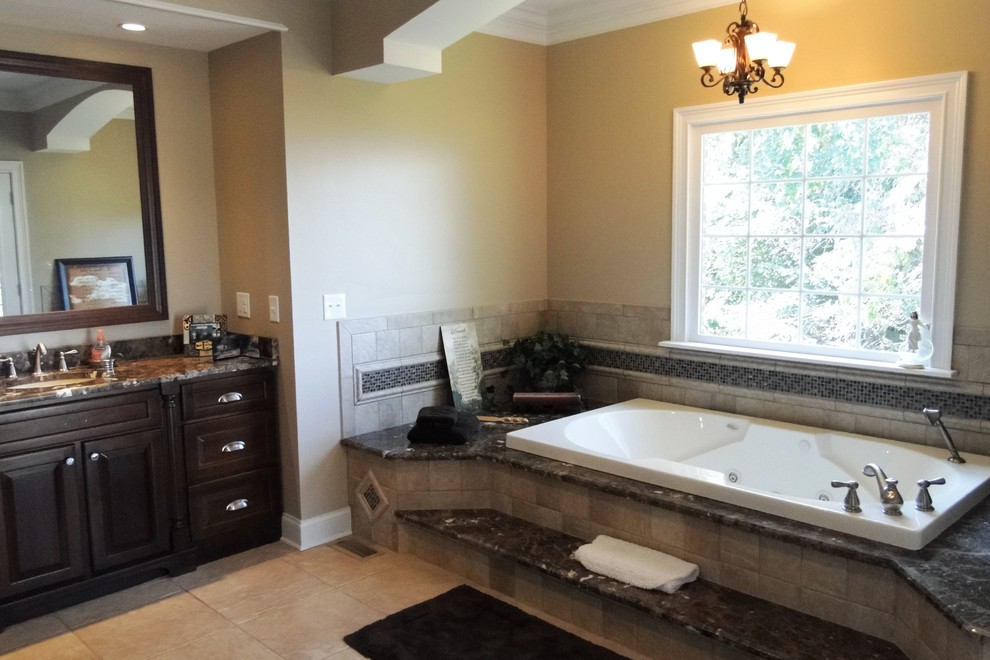Photo of a large transitional master bathroom in Other with an undermount sink, recessed-panel cabinets, dark wood cabinets, granite benchtops, a hot tub, a double shower, a one-piece toilet, beige tile, porcelain tile, beige walls and porcelain floors.