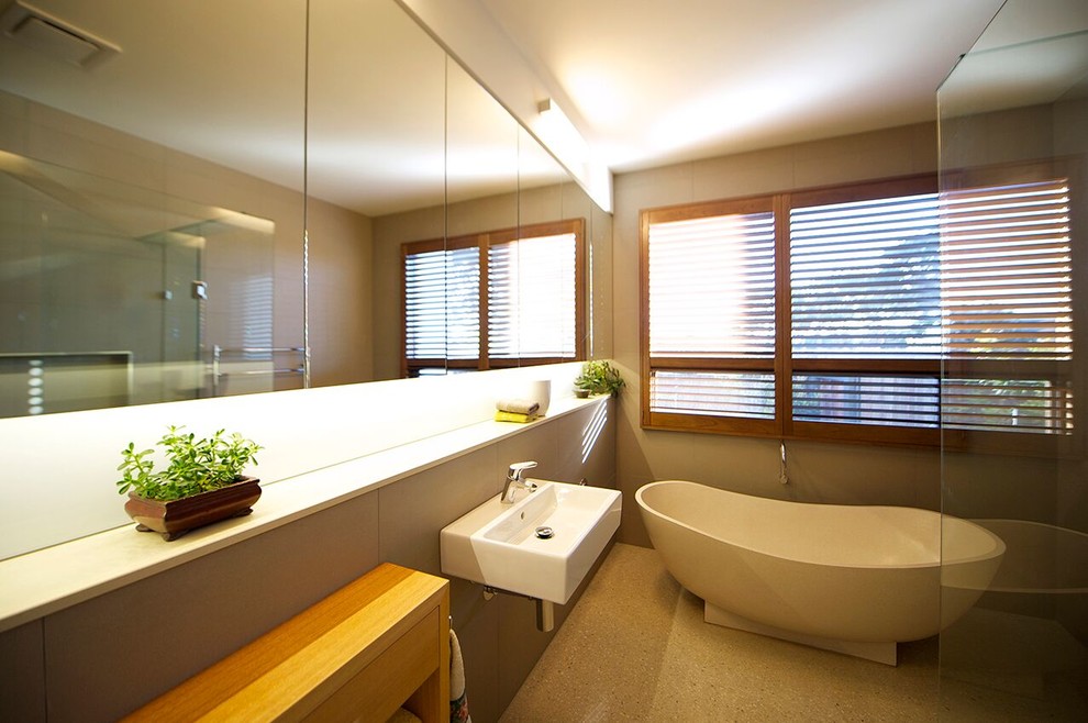 Mid-sized contemporary master bathroom in Geelong with a freestanding tub, an alcove shower, gray tile, porcelain tile, grey walls, concrete floors, a wall-mount sink, beige floor, a hinged shower door, engineered quartz benchtops, furniture-like cabinets, light wood cabinets and white benchtops.