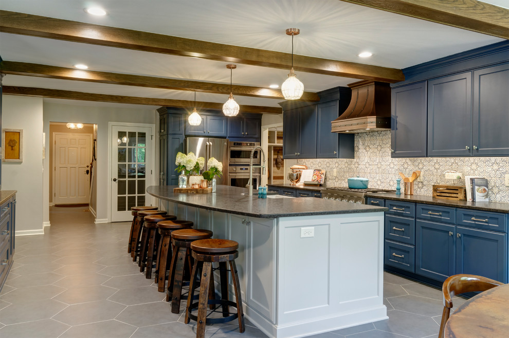 This is an example of a large traditional single-wall eat-in kitchen in Columbus with a farmhouse sink, shaker cabinets, blue cabinets, granite benchtops, multi-coloured splashback, porcelain splashback, stainless steel appliances, ceramic floors, with island, grey floor and black benchtop.