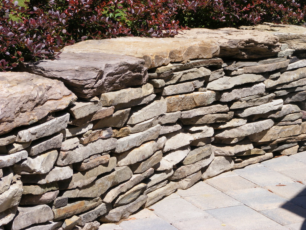 Inspiration for a large transitional partial sun backyard stone retaining wall landscape for summer.